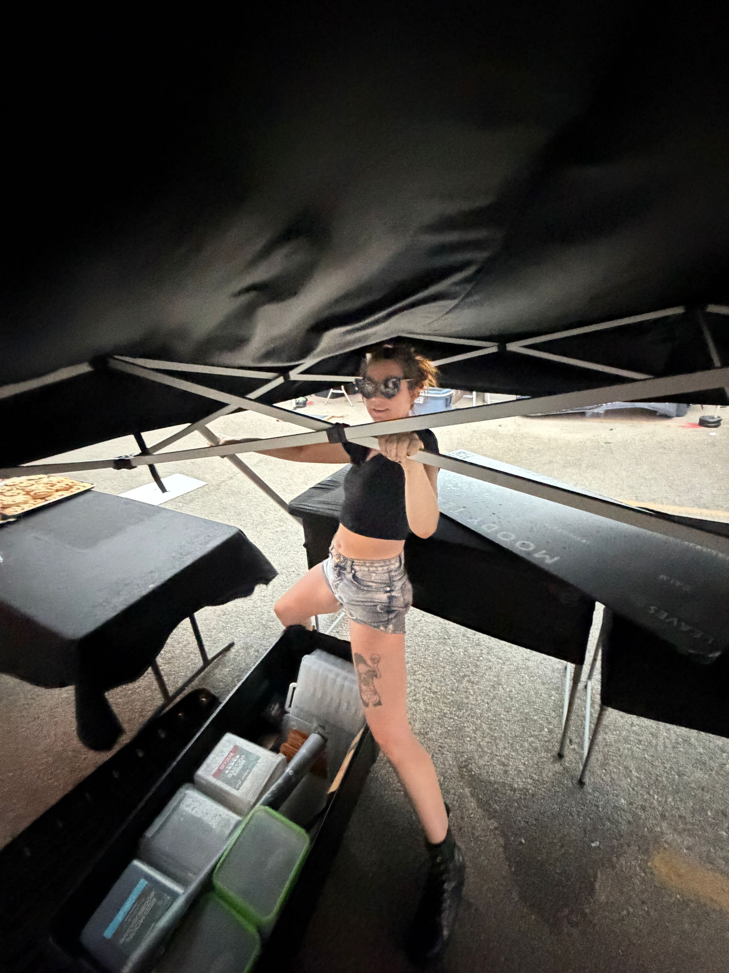 Moody Teas market manager Cat holding the tent frame down during a storm